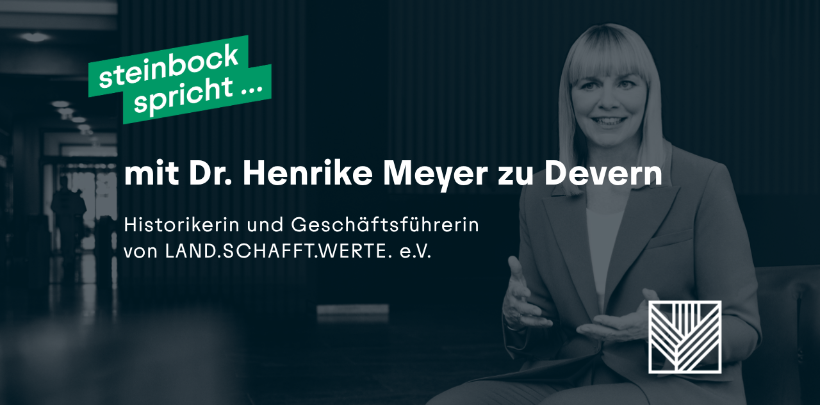 Eine Frau mit hellem, schulterlangem Haar sitzt in einem modernen Innenraum auf einem Stuhl. Sie trägt einen hellen Blazer und hält die Hände vor dem Körper. Links im Bild steht in weißer Schrift auf grünem Hintergrund: 'steinbock spricht ...'. Darunter folgt in weißer Schrift: 'mit Dr. Henrike Meyer zu Devern'. In kleinerer Schrift darunter: 'Historikerin und Geschäftsführerin von LAND.SCHAFFT.WERTE. e.V.'. Unten rechts befindet sich ein grafisches Logo mit stilisierten Linien.