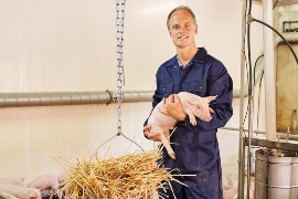 Hendrik Klein-Heßling of Klein-Hessling farm with a piglet. (Sustainable project: Klein-Hessling farm)